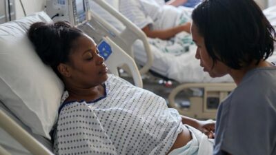 A maternity ward scene showing a Black woman being comforted by a nurse - via eurAI