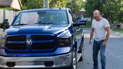 Angry white man standing next to his crashed pick-up truck - via eurAI