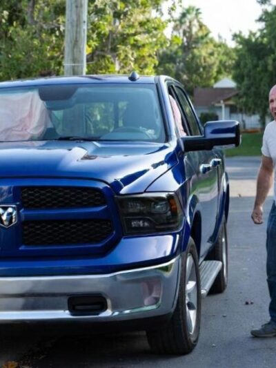 Angry white man standing next to his crashed pick-up truck - via eurAI