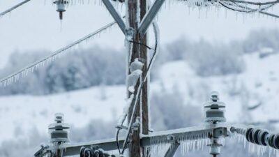 Close-up of a frozen utility line and power pole dealig withweight of ice, symbolizing power outage risk - via eurAI