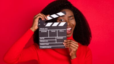 Black woman in red holding a hold clapboard