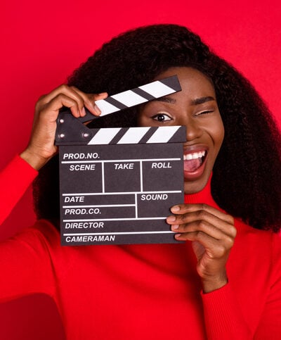 Black woman in red holding a hold clapboard