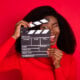 Black woman in red holding a hold clapboard