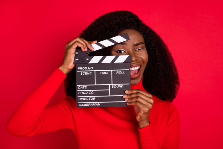Black woman in red holding a hold clapboard