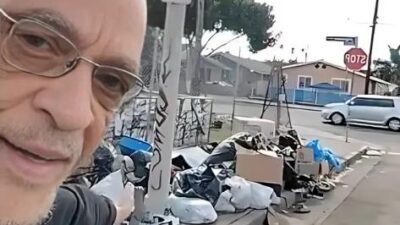 Earl Ofari Hutchinson points to garbage dumping on South LA street corner - screenshot