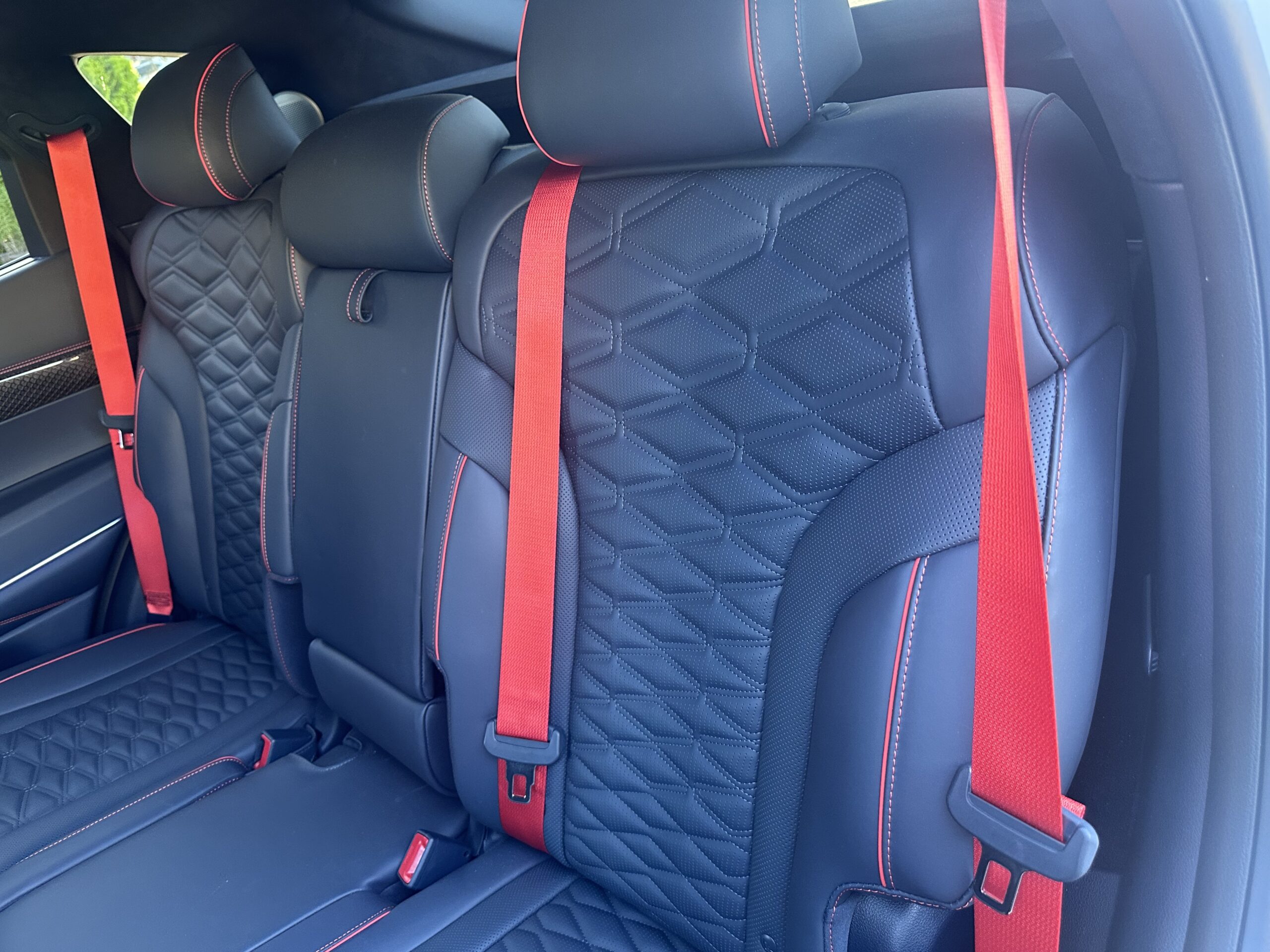 dark colored vehicle seats with red seatbelts