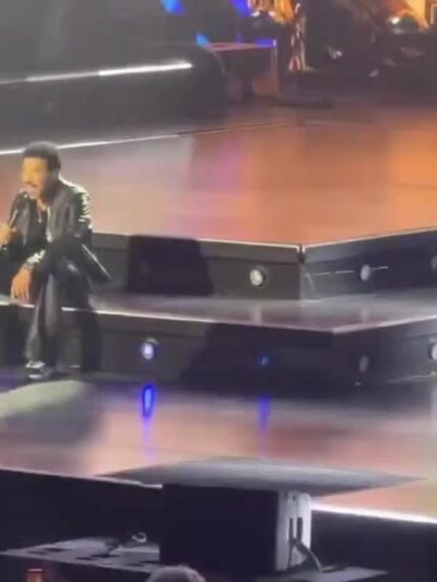 Lionel Richie sitting on stage after falling ill - screenshot