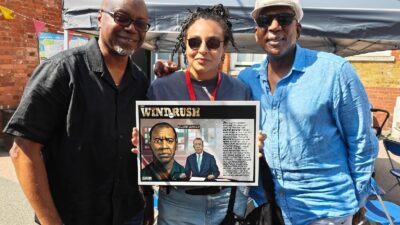 Tayo, Nelle Porter and actor Colin McFarlane both of Justice 4 Windrush with one of Tayo's donated illustrations to school
