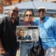 Tayo, Nelle Porter and actor Colin McFarlane both of Justice 4 Windrush with one of Tayo's donated illustrations to school