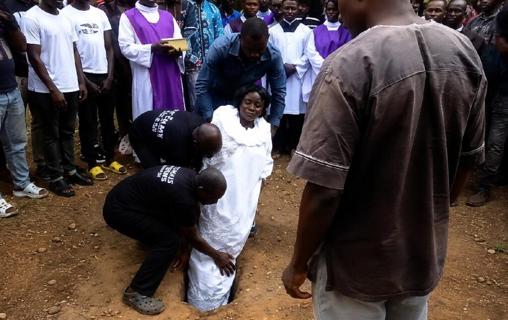 African woman being buried vertically - screenshot