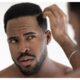 Close up anxious unhappy African American man checking hair after shower, looking in mirror, standing in bathroom at home, dissatisfied by hair loss or dandruff, healthcare and beauty concept