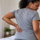 Adult holding the flank area of the mid-back in discomfort (back pain) - via eurAI
