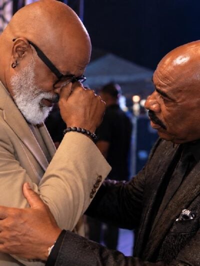Editorial depiction of two Black comedians (Jonathan Slocumb and Steve Harvey) reconciling backstage
