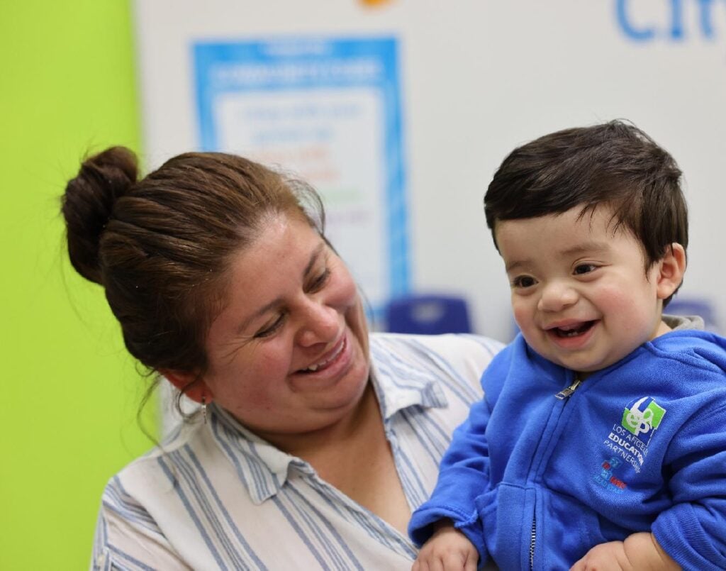 Smiling caregiver holds happy toddler at early learning center